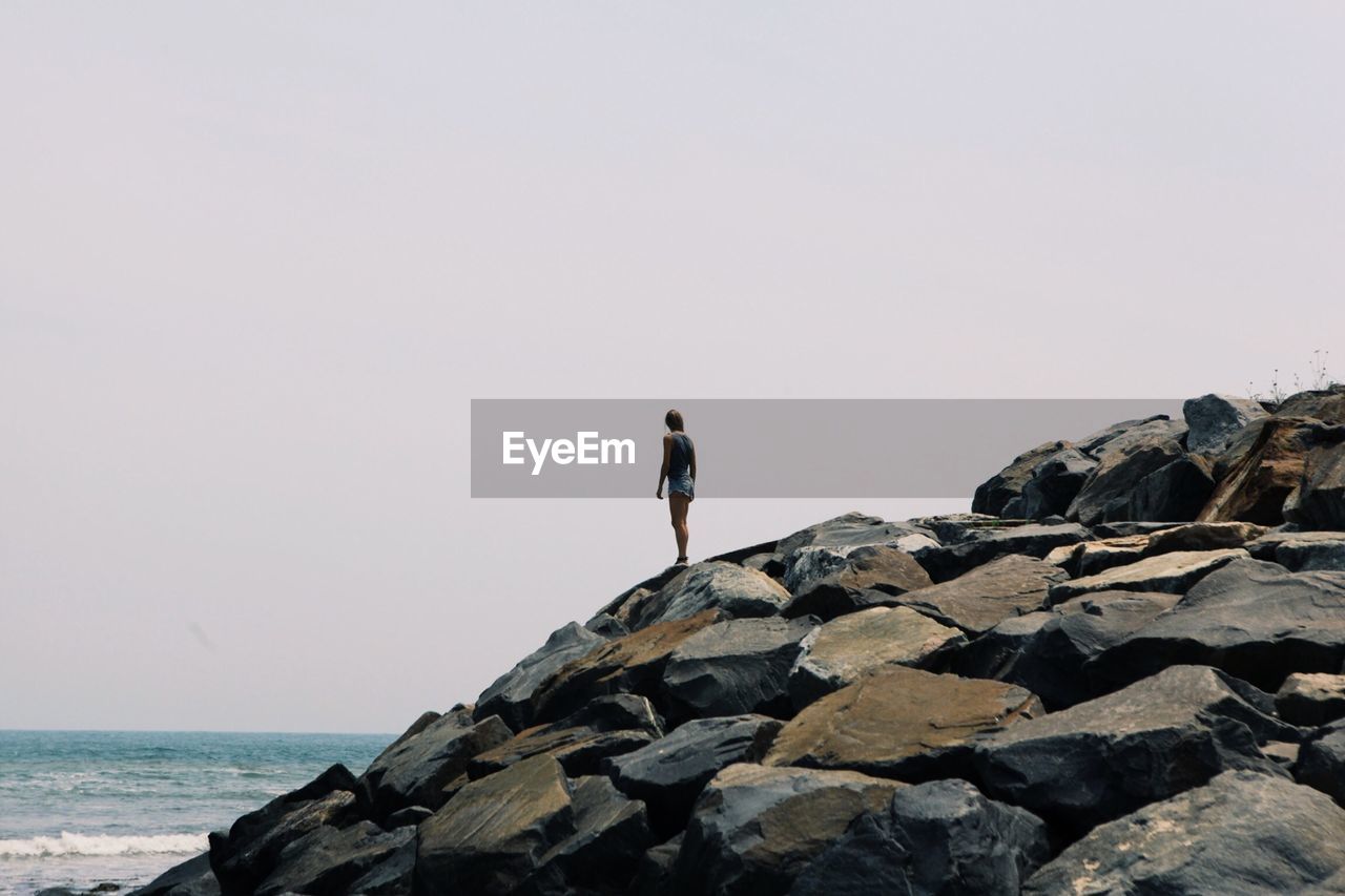 Woman standing on rocks at coast