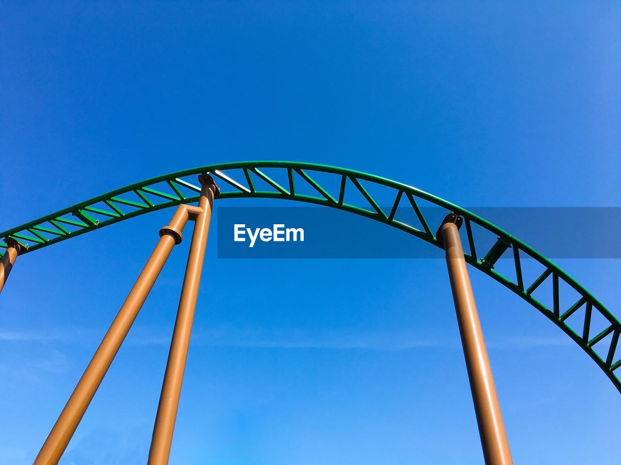 Low angle view of rollercoaster against clear blue sky