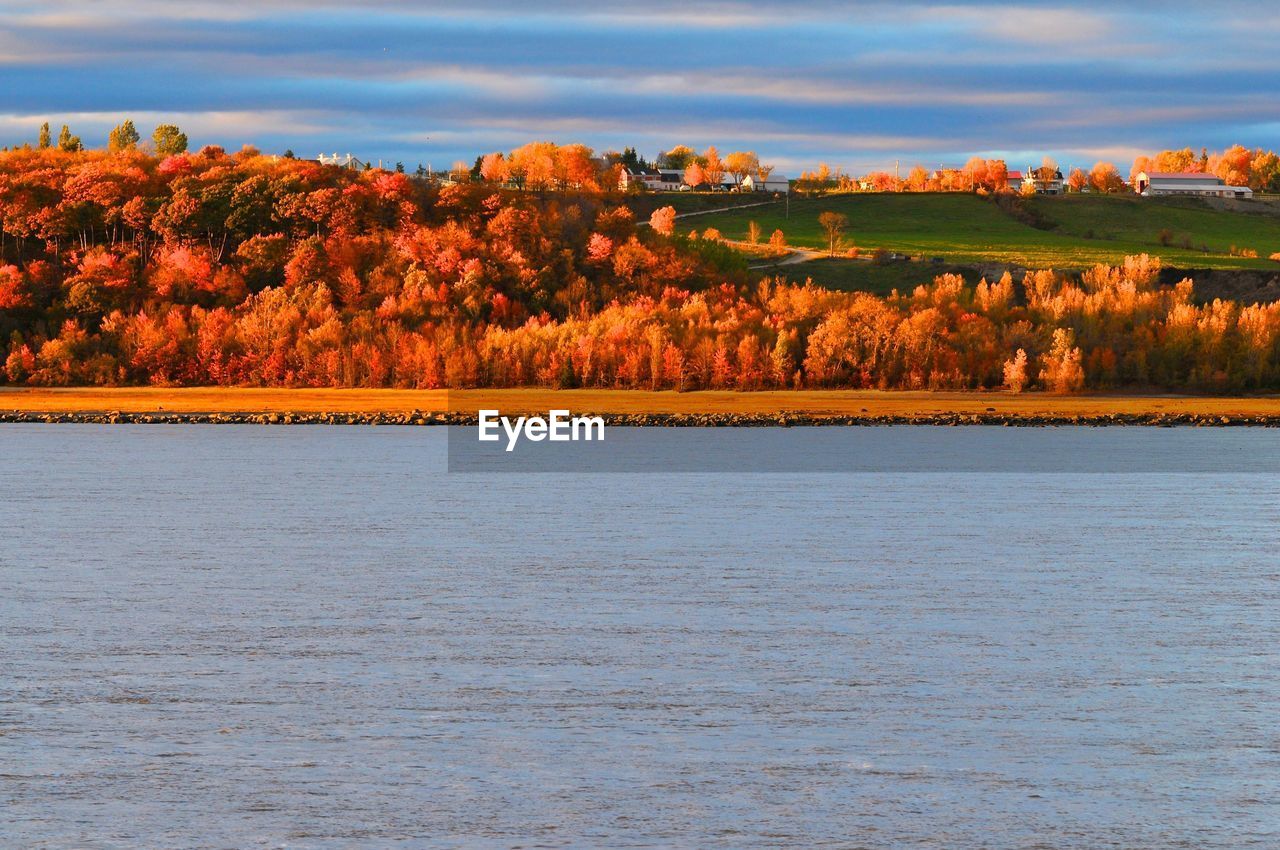 Scenic view of sea by hill against sky during autumn