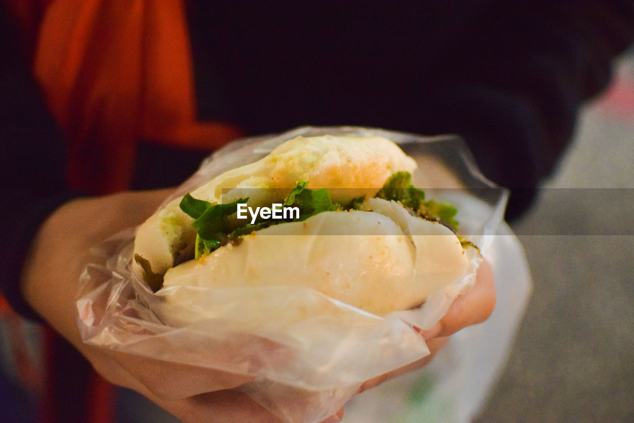CLOSE-UP OF HAND HOLDING BREAD IN PLATE
