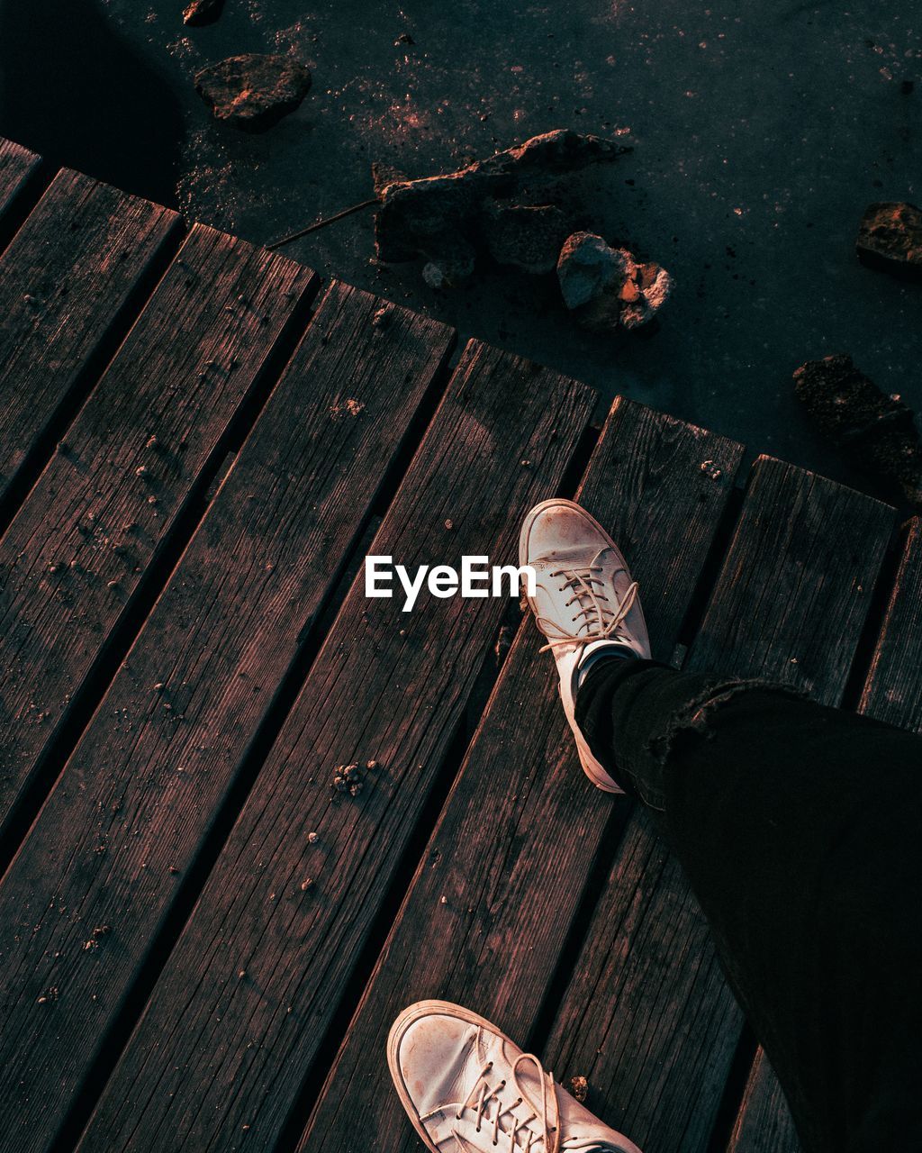 LOW SECTION OF MAN STANDING ON WOODEN BOARDWALK