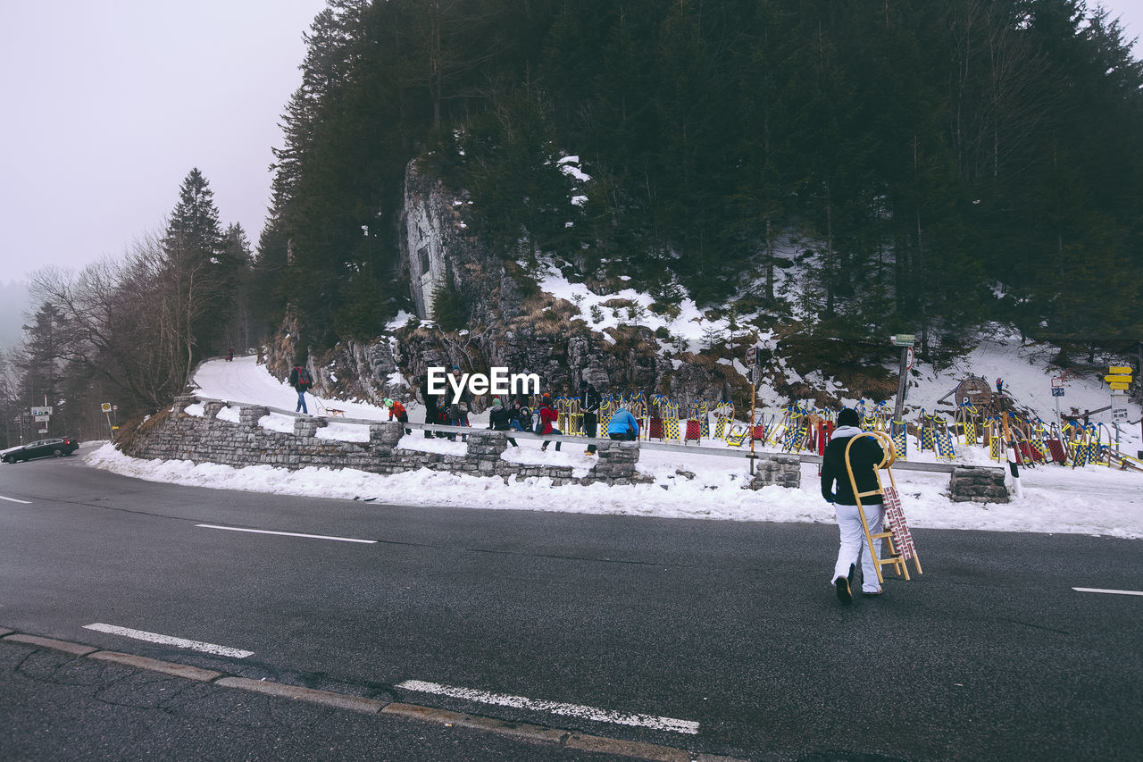 Rear view of man crossing road during winter