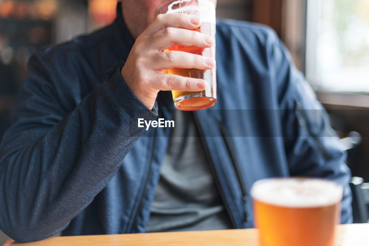 Midsection of man drinking beer in restaurant