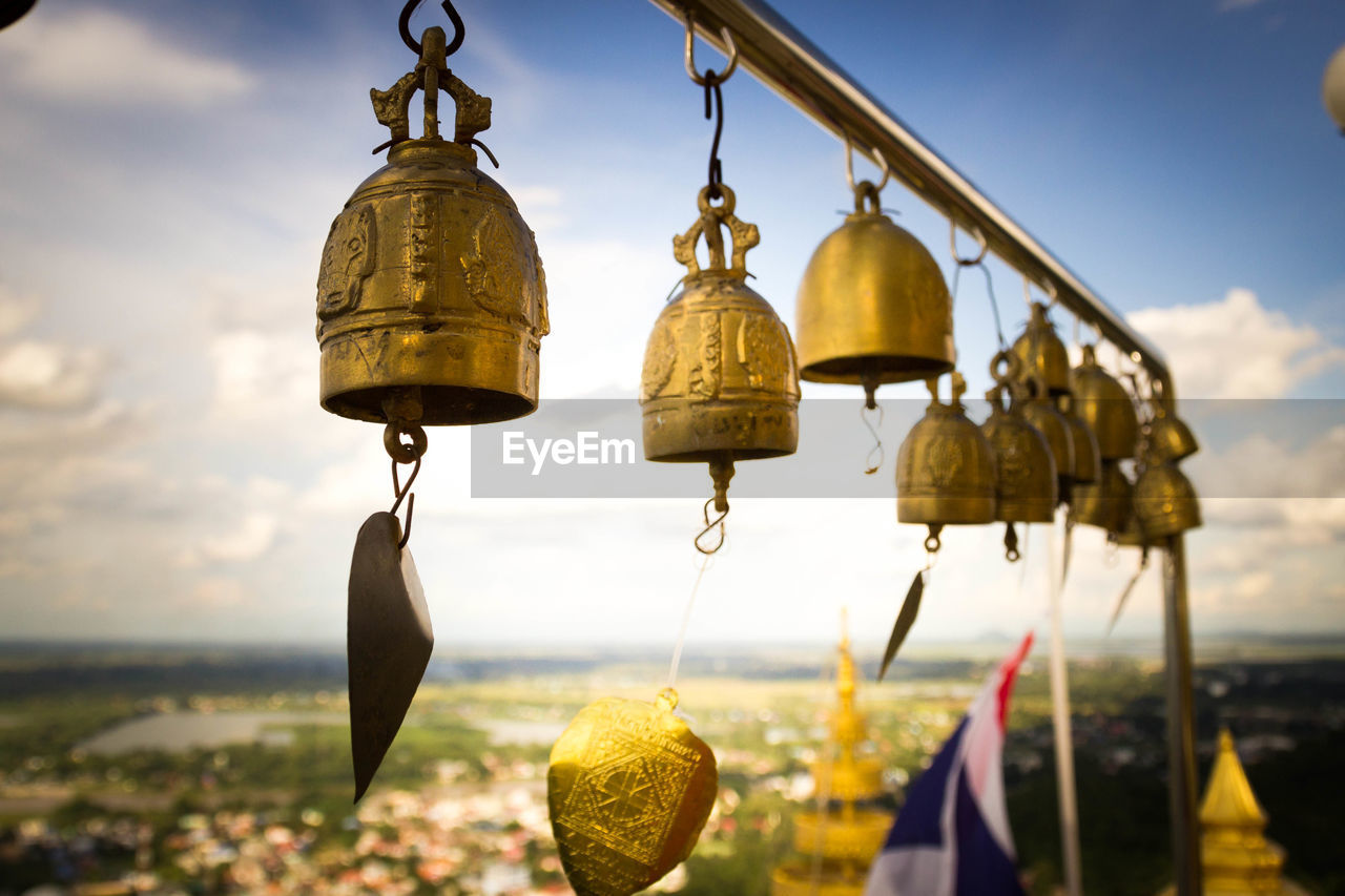 Golden bells hanging at temple against sky