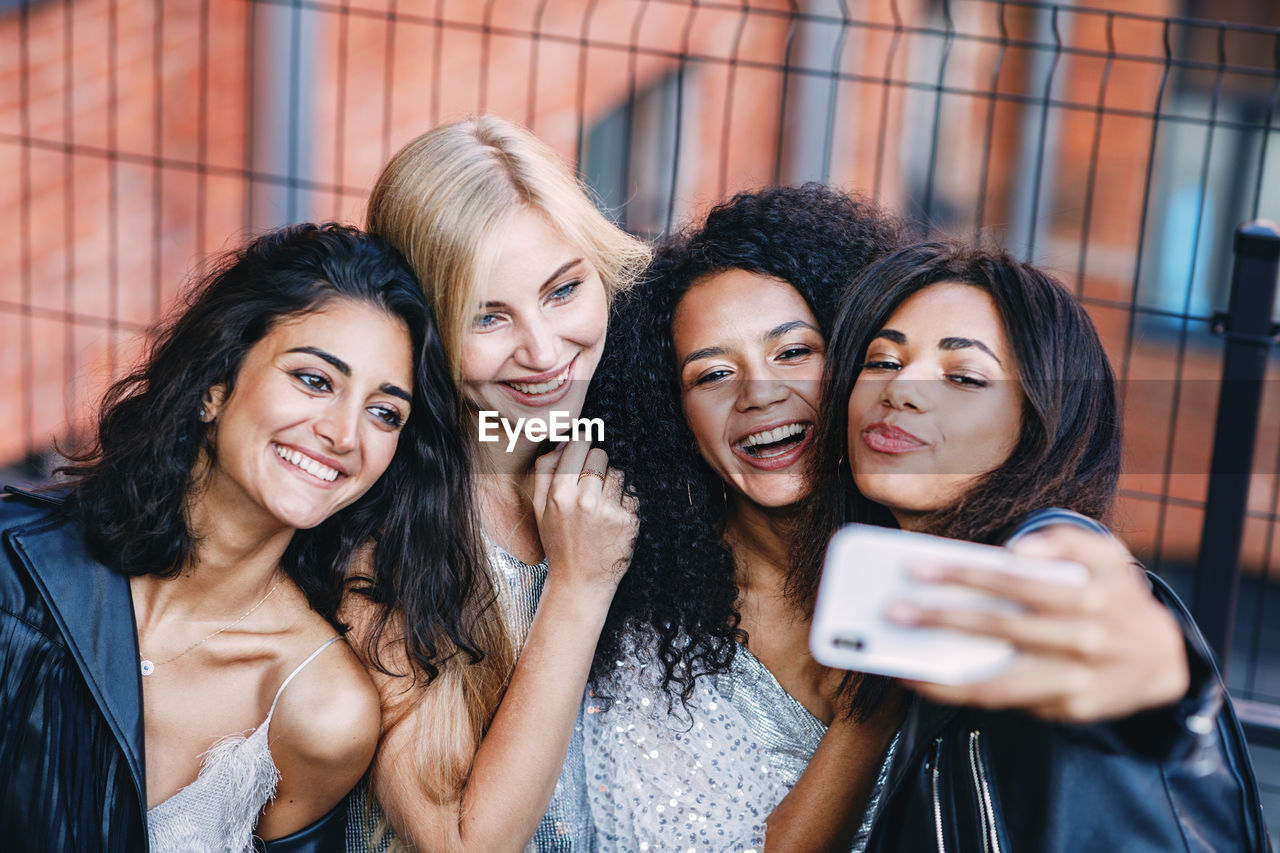 PORTRAIT OF SMILING YOUNG WOMAN USING MOBILE PHONE IN TRADITIONAL