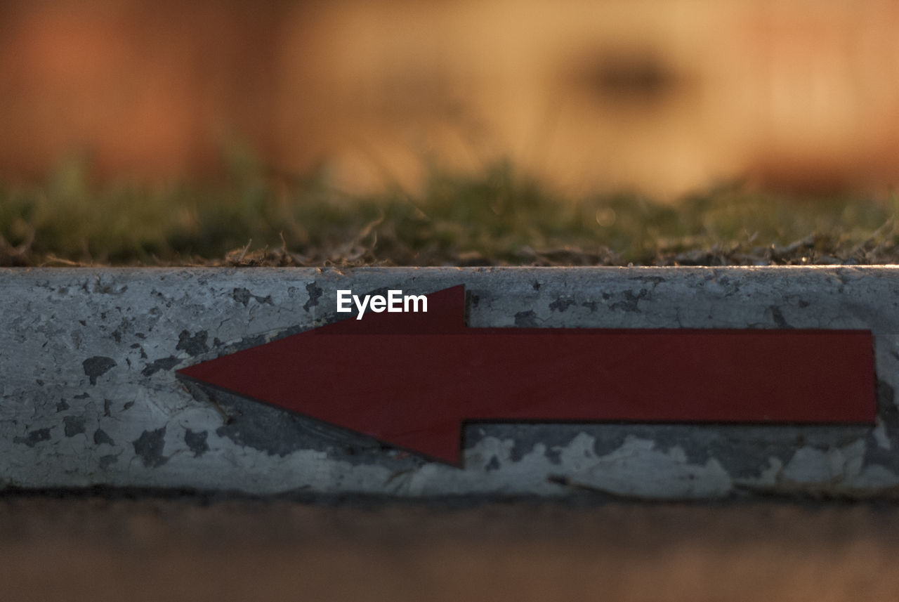 Close-up of red arrow sign on retaining wall
