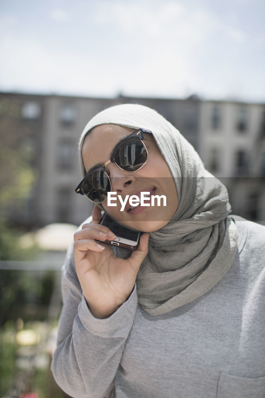 Muslim woman wearing a hijab and sunglasses taking a phone call