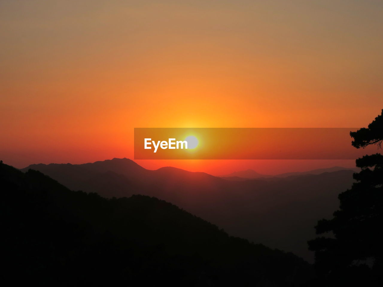 Silhouette mountains against orange sky during sunset