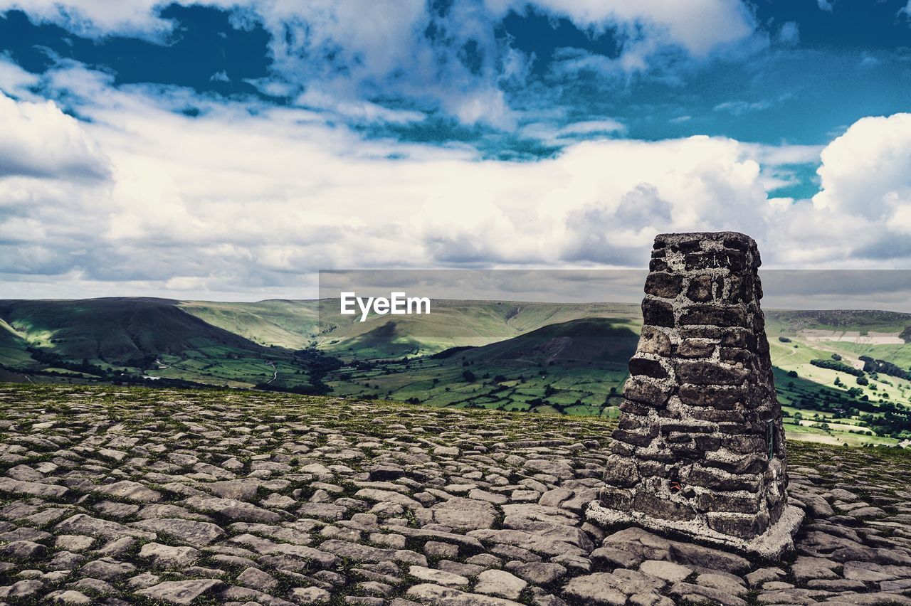 Built structure by landscape against sky