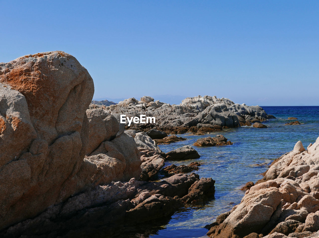 Scenic view of rocks in sea against clear sky