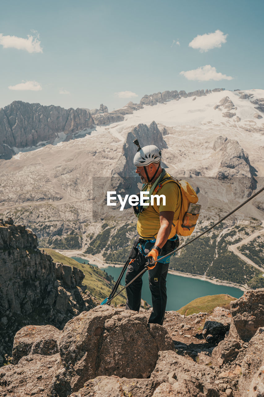 MAN ON ROCKS AGAINST MOUNTAIN RANGE