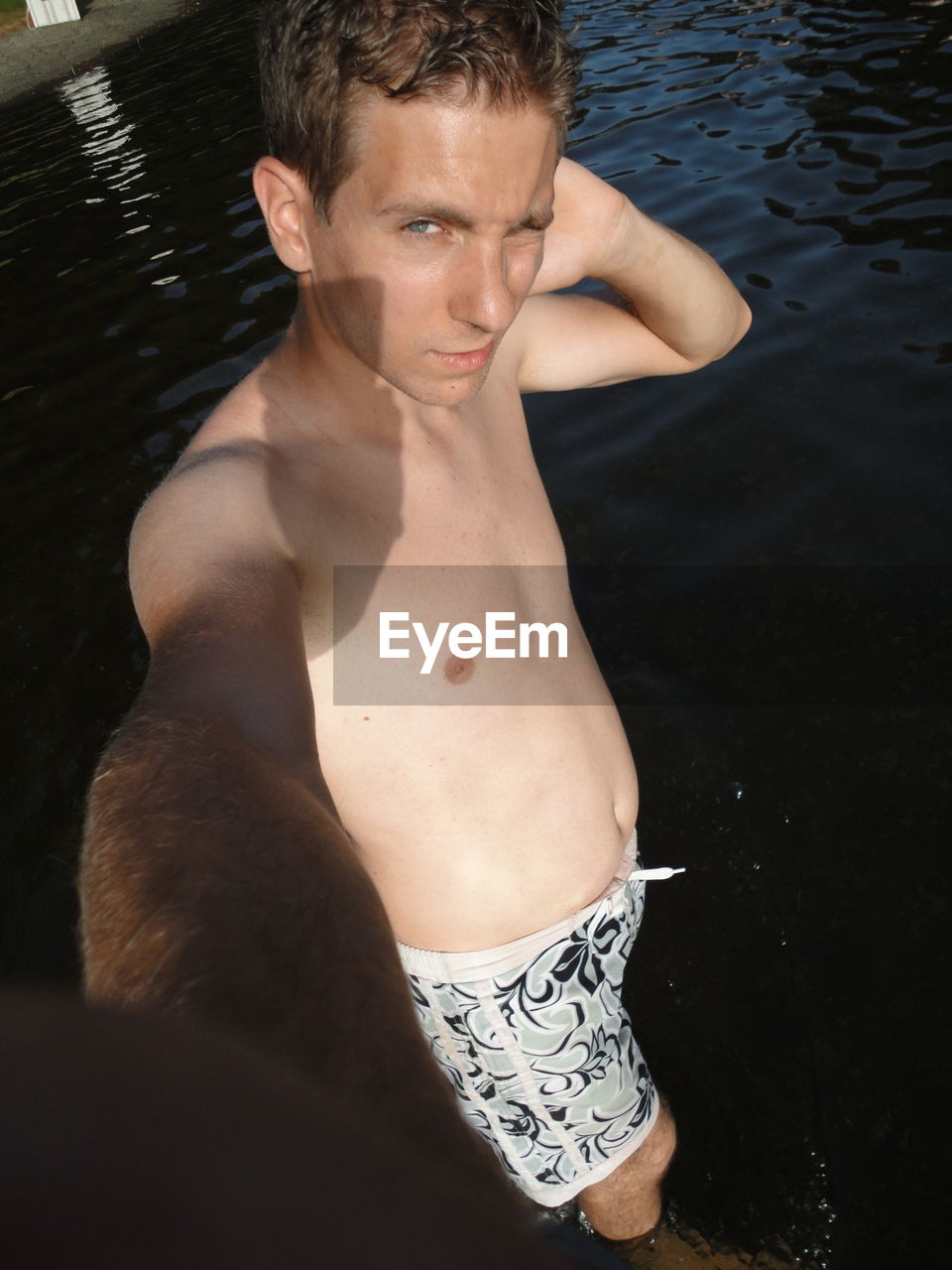 Portrait of shirtless man standing in lake