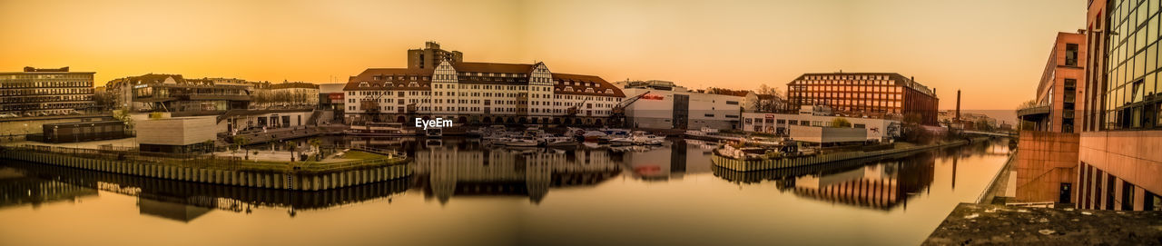 Sailboats moored in river against buildings in city