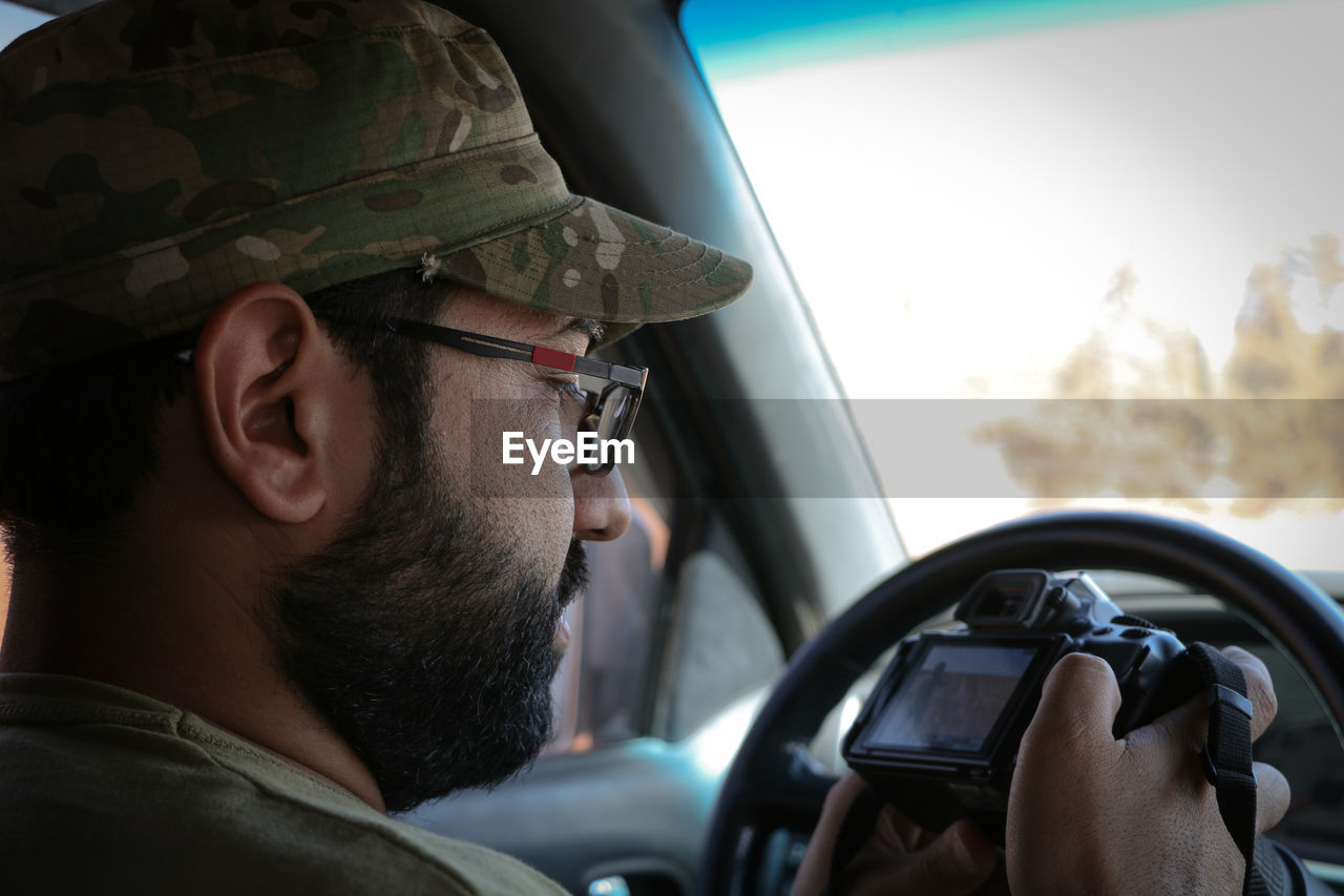 Man holding camera while sitting in car