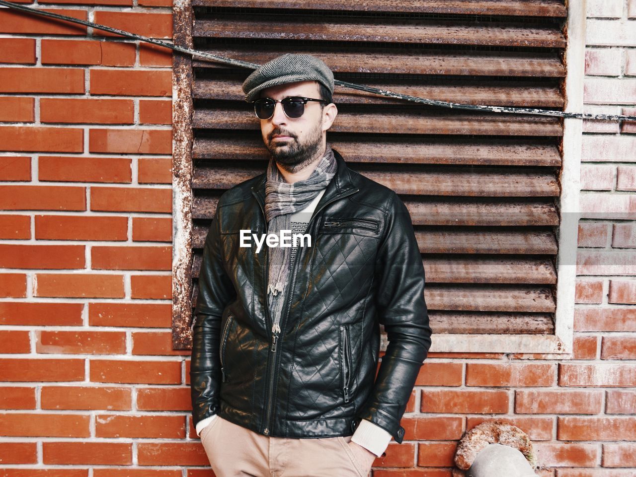 Mid adult man wearing sunglasses standing against brick wall