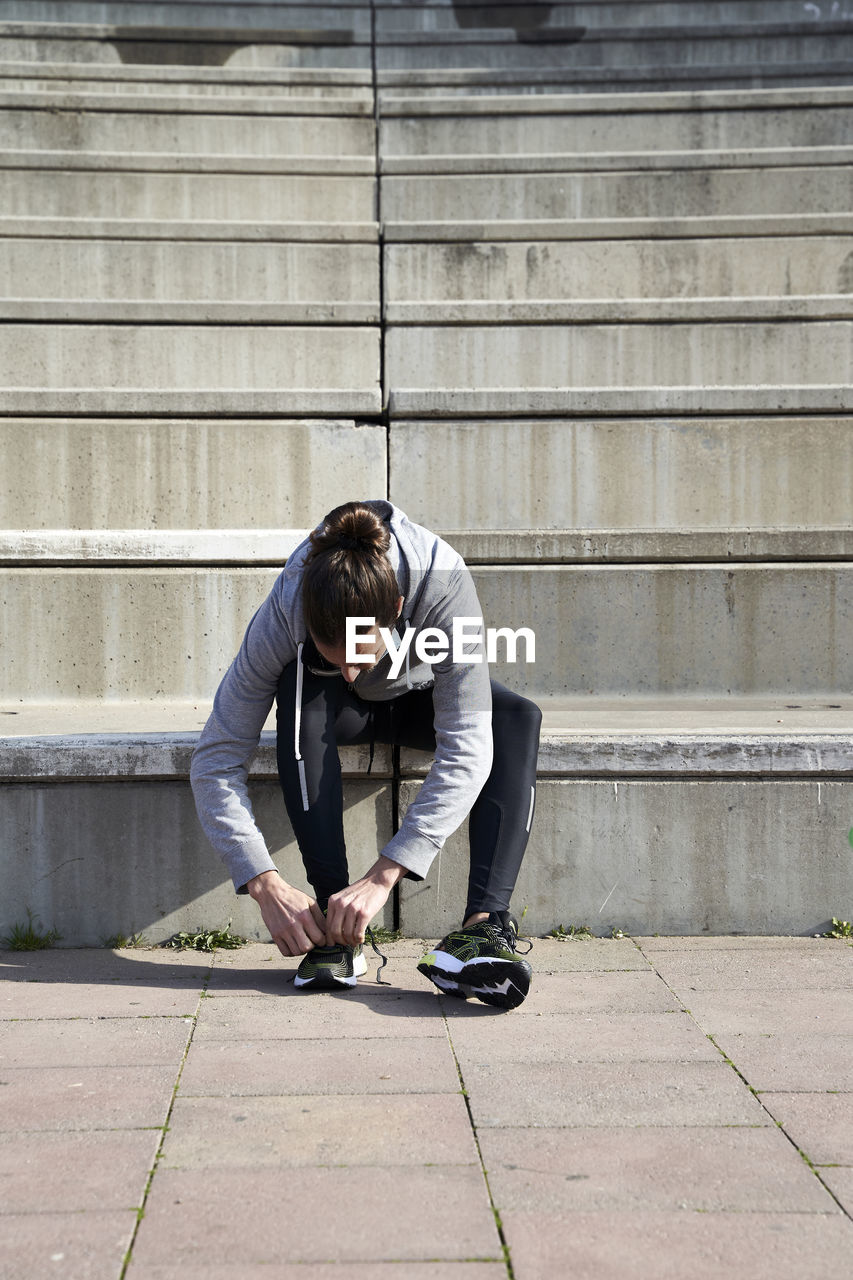 Man tying shoelace while sitting on steps