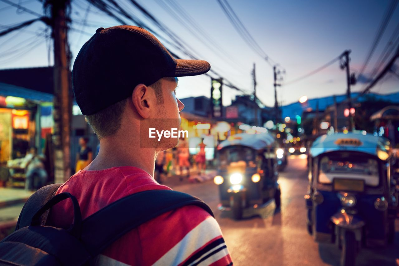 Rear view of young man walking on street at dusk