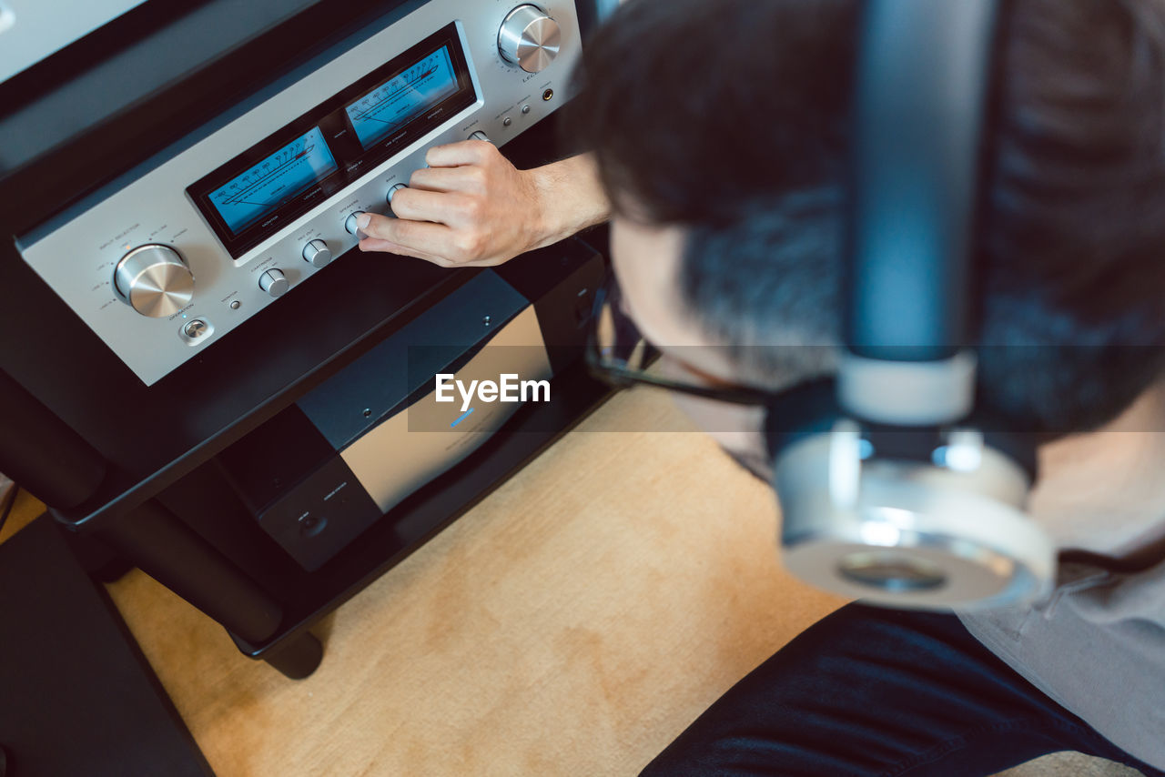 High angle view of man adjusting while listening music on table