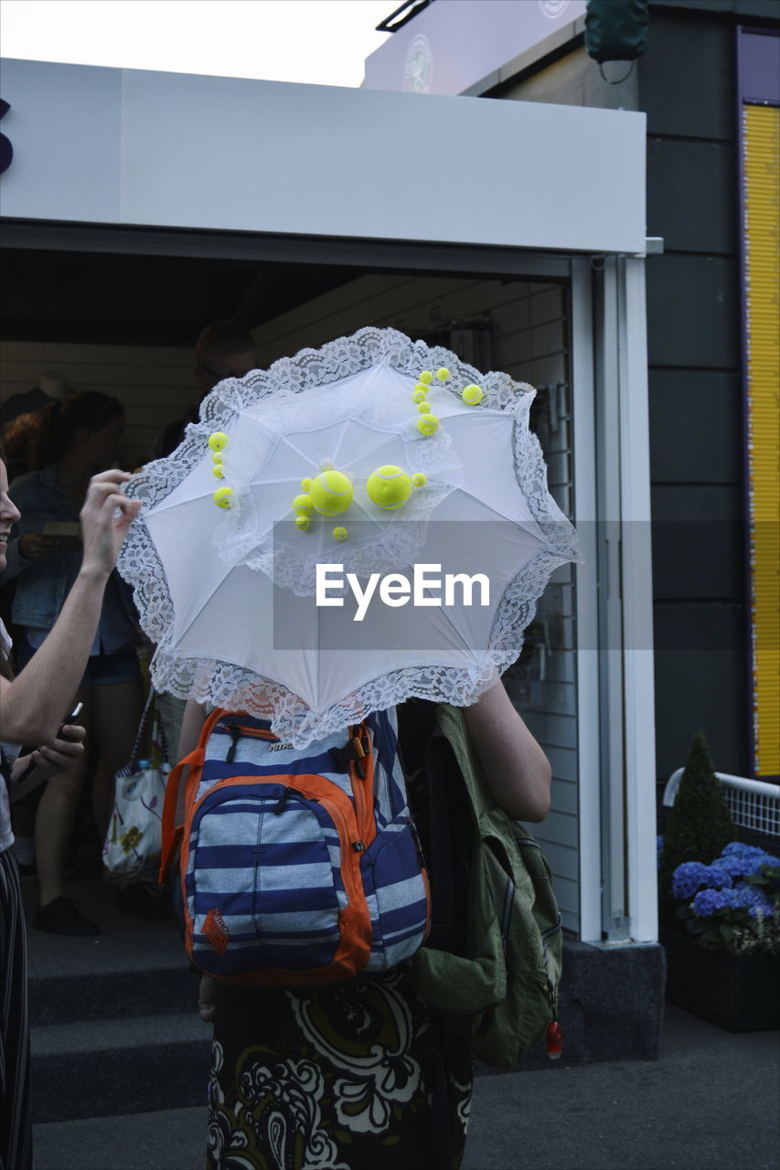 Rear view of woman with tennis ball umbrella 