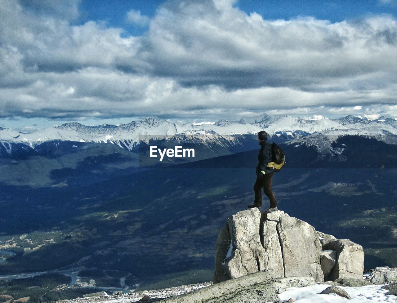 Hiker standing on rock against mountains