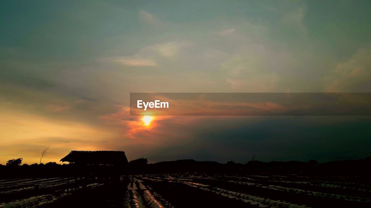 PANORAMIC VIEW OF AGRICULTURAL FIELD AGAINST SKY DURING SUNSET