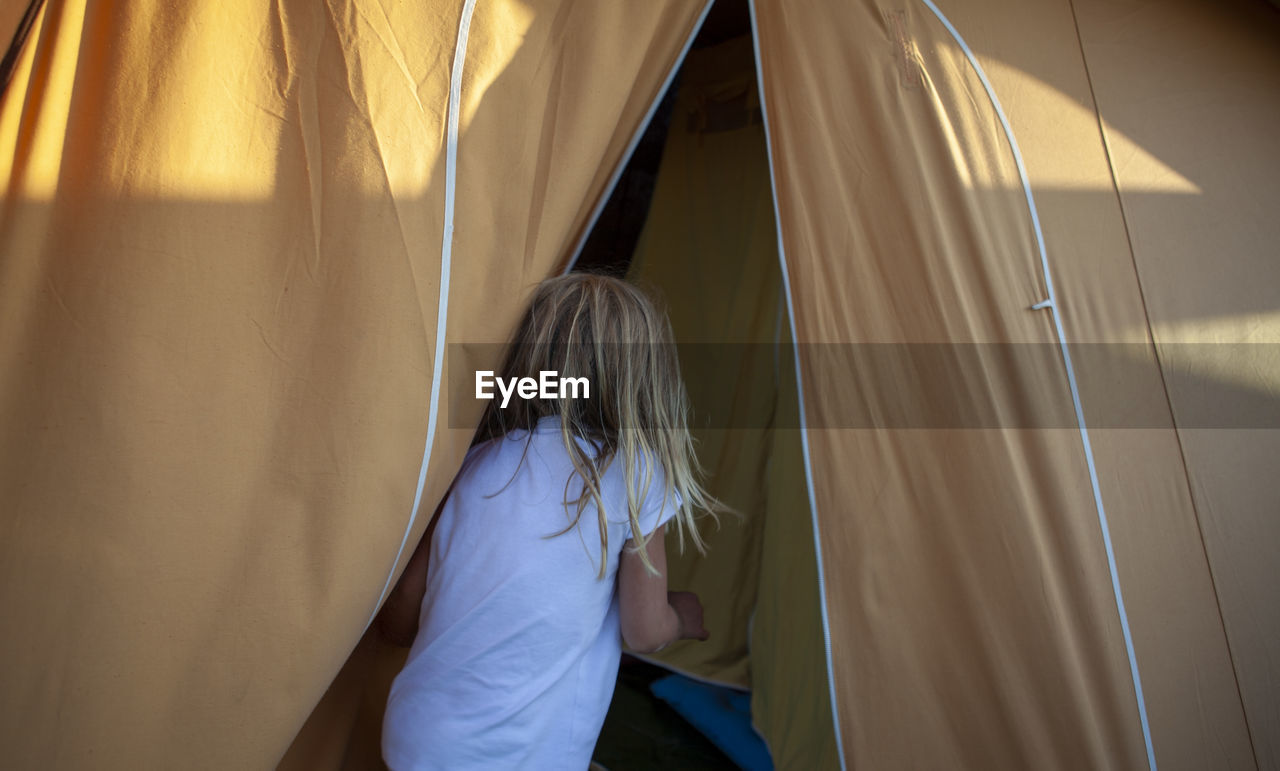 Rear view of girl in tent at home