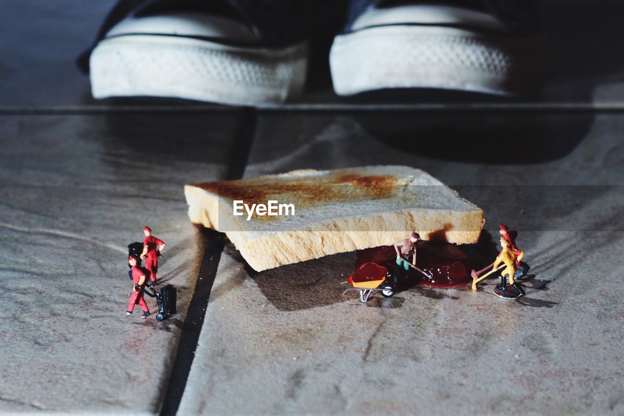 Artistic image of figurines cleaning bread and jam fallen on floor