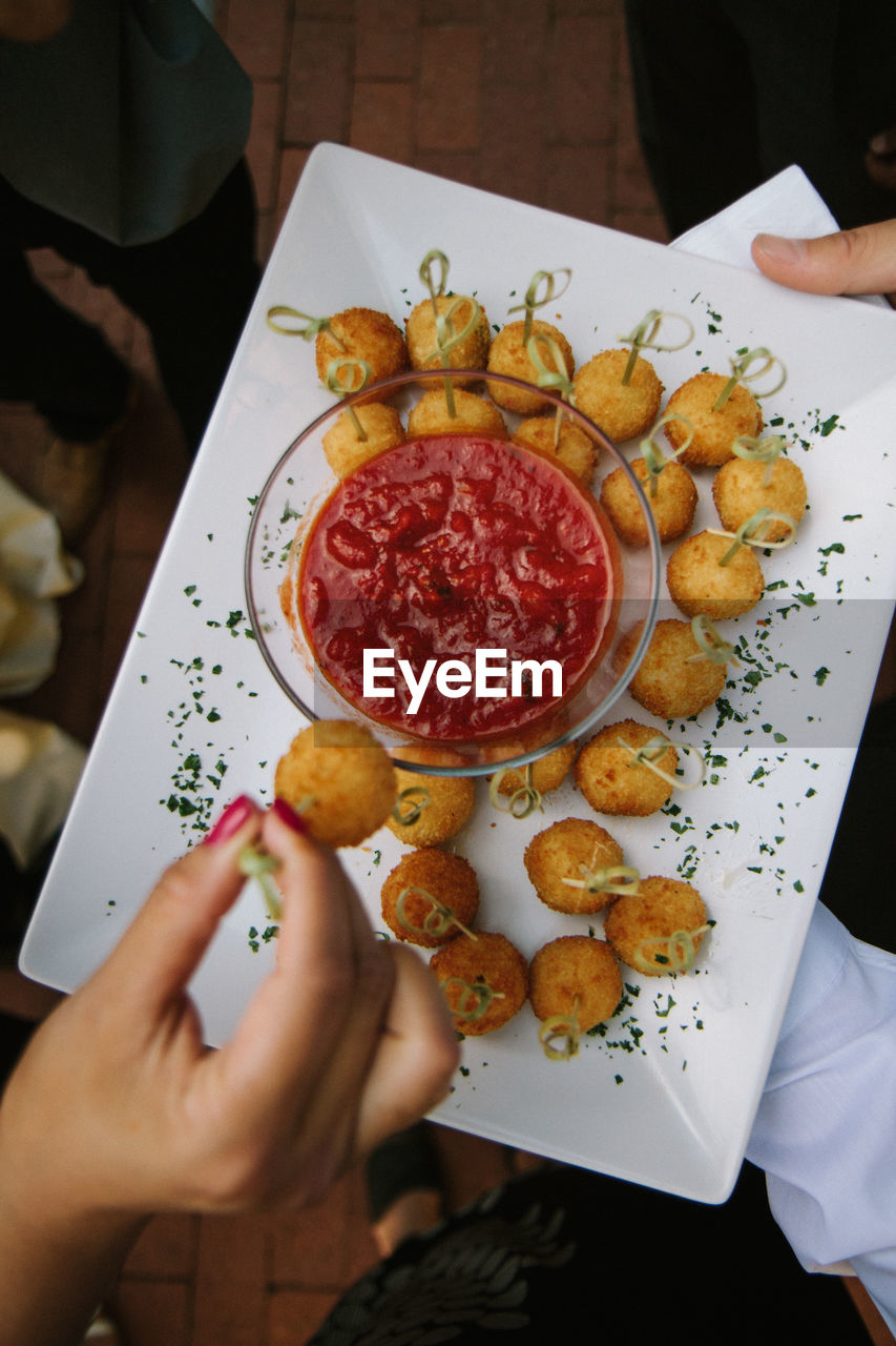 Appetizer plate from above with hand dipping food into sauce
