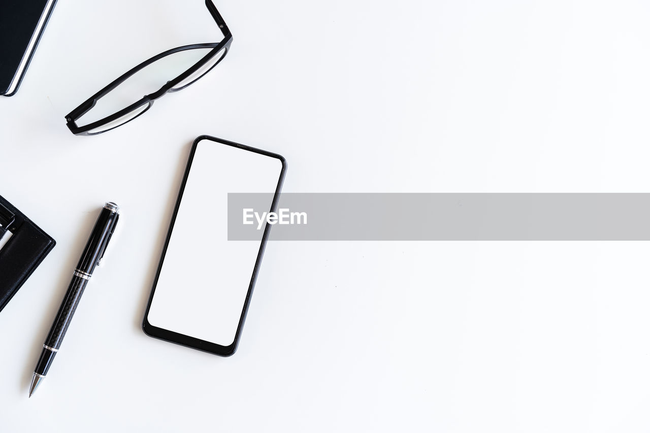 HIGH ANGLE VIEW OF SMART PHONE ON WHITE TABLE