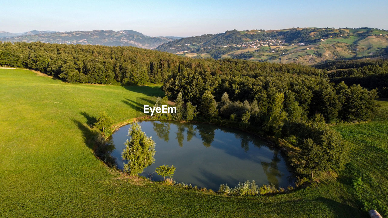 Scenic aerial view from the drone of a little lake with trees and hills