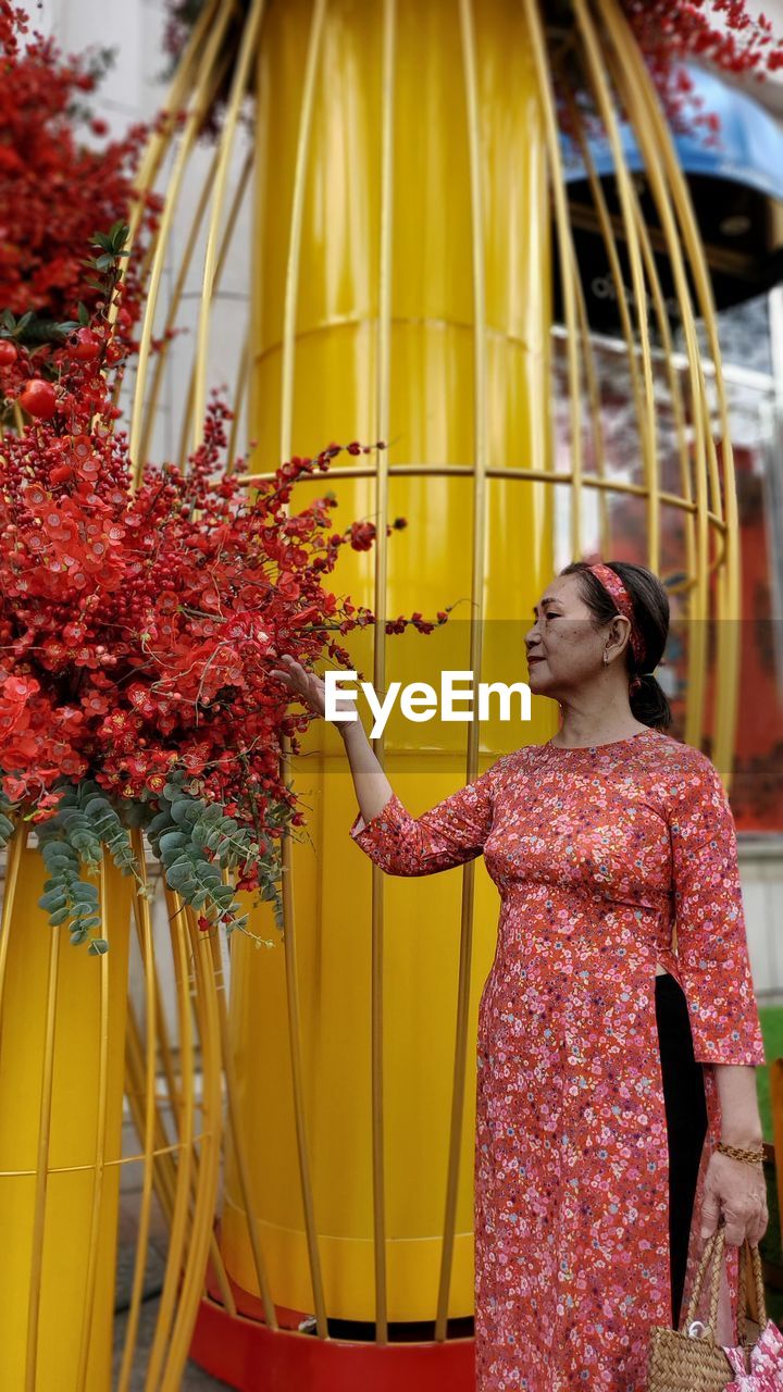 Mature woman touching flower decoration outdoors