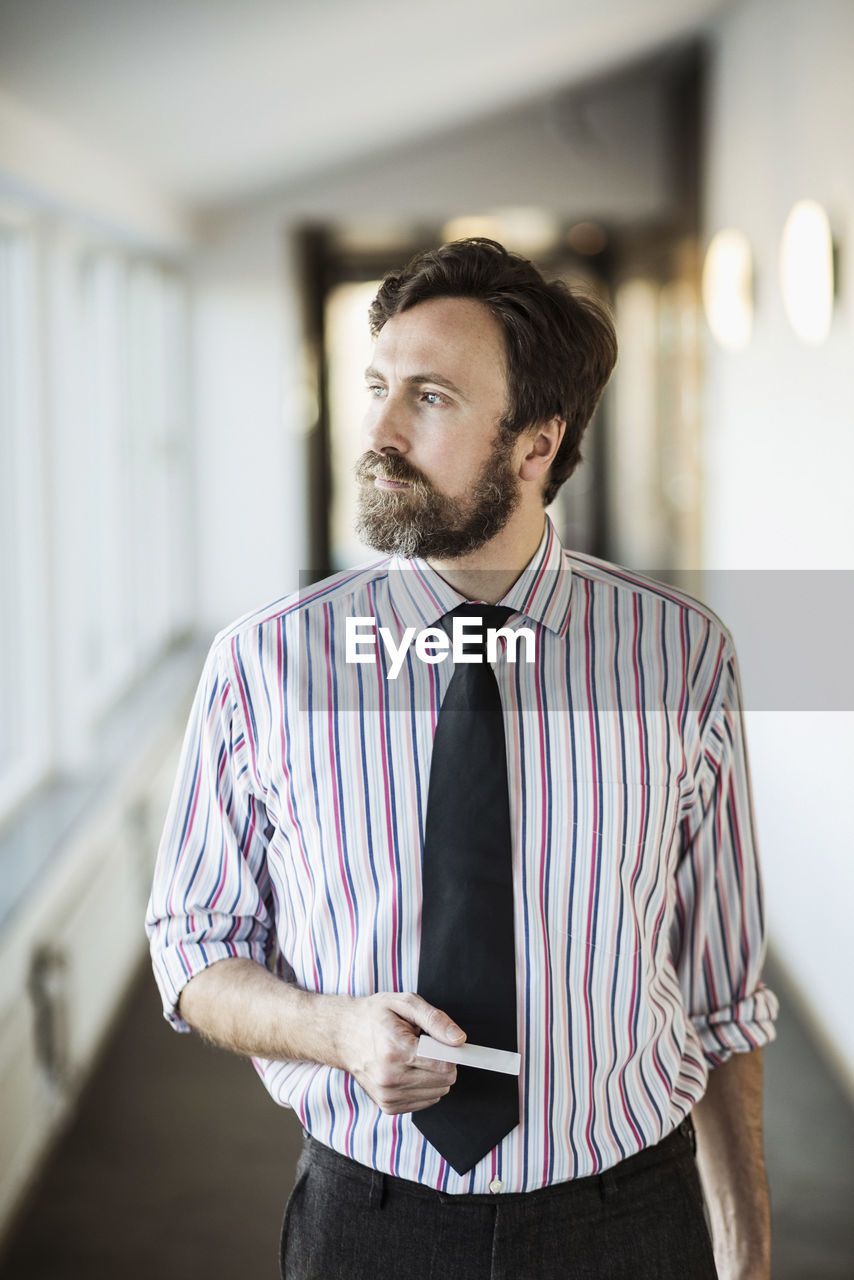 Businessman looking away while holding cardkey in hotel