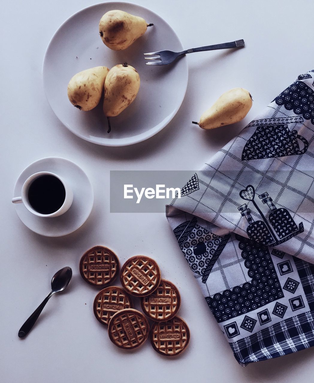 Directly above shot of black coffee with cookies and pears on table
