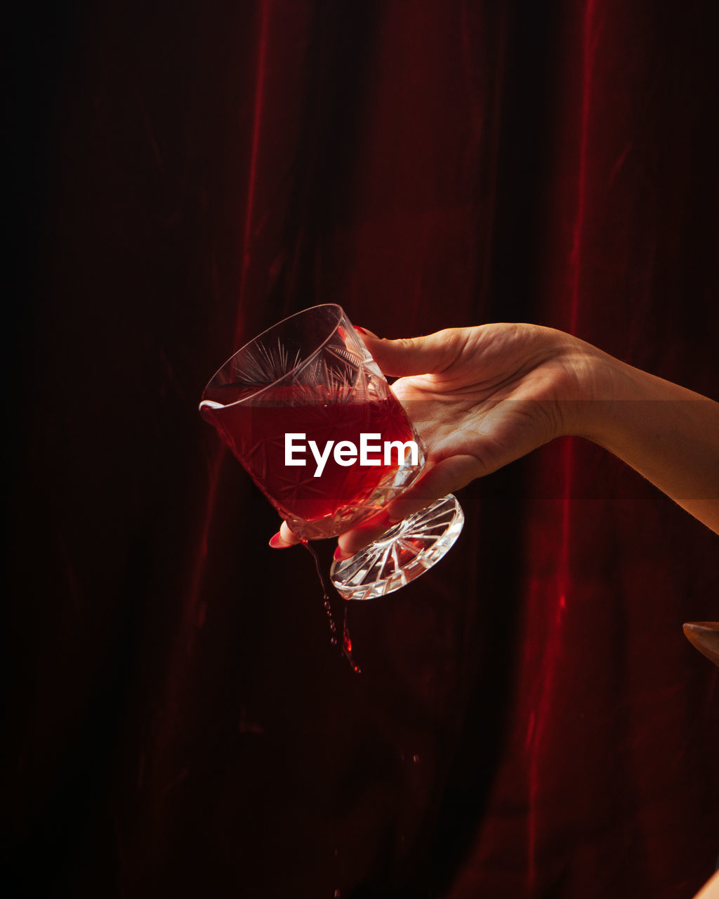 CLOSE-UP OF HAND HOLDING GLASS OF RED WINE