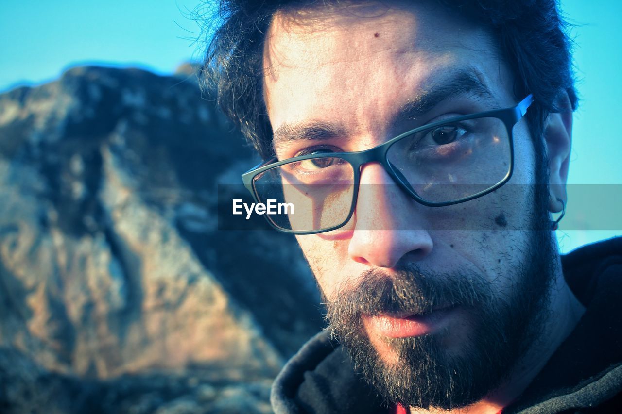 Portrait of young man wearing eyeglasses against rock formation