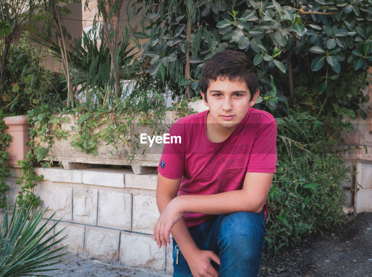 Portrait of boy kneeling against plants in park