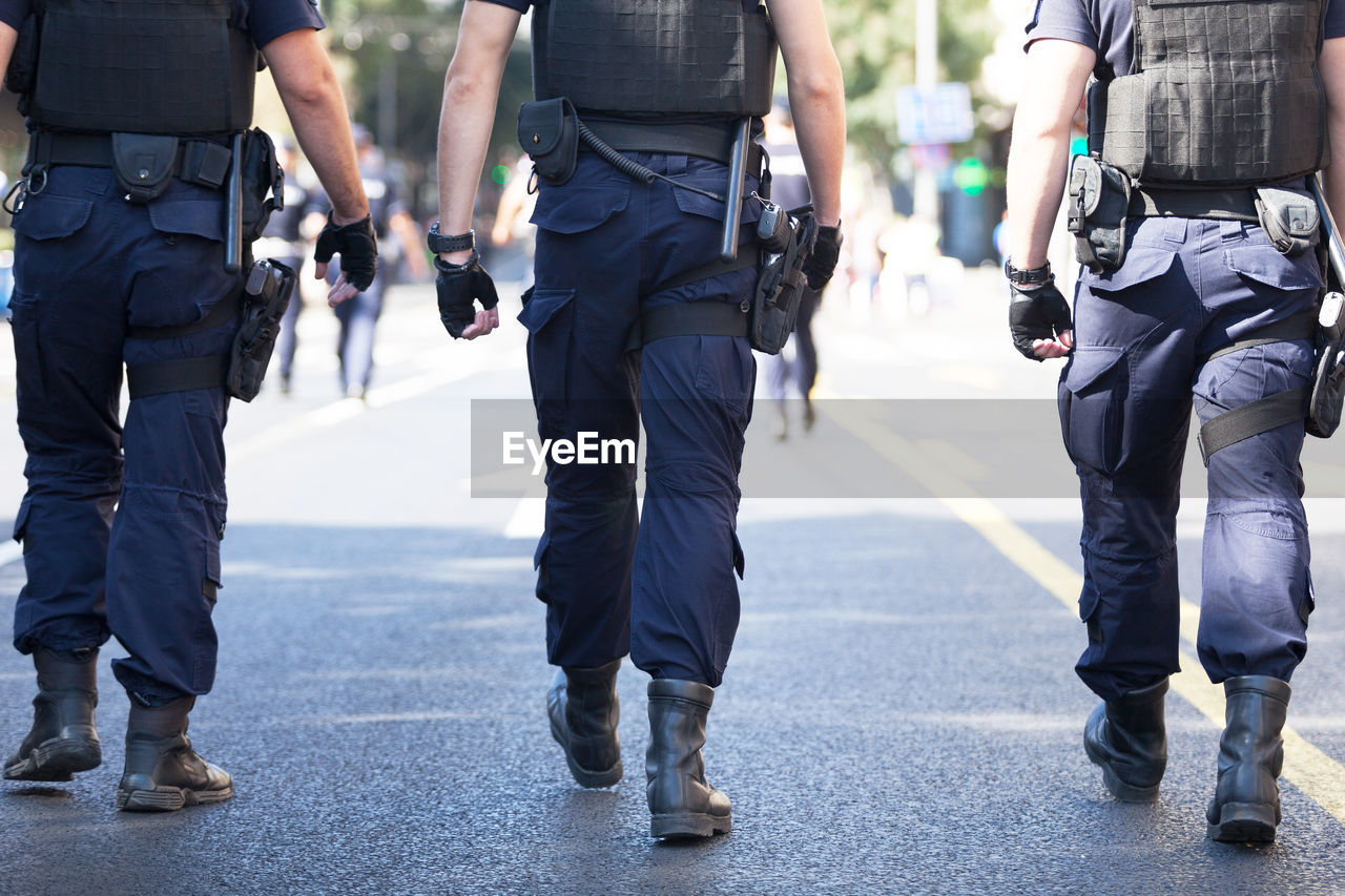 Low section of police men walking on street in city