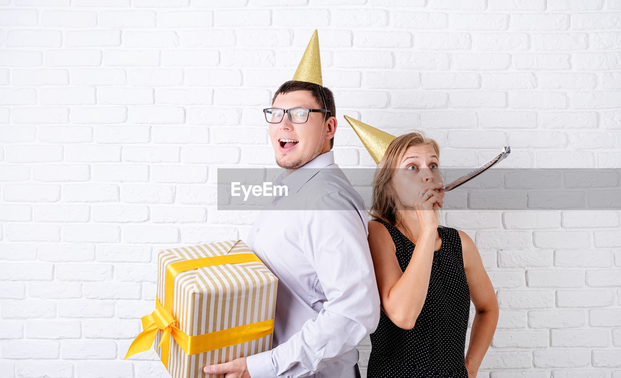 Funny couple celebrating birthday. young woman blowing a noisemaker having fun at the party