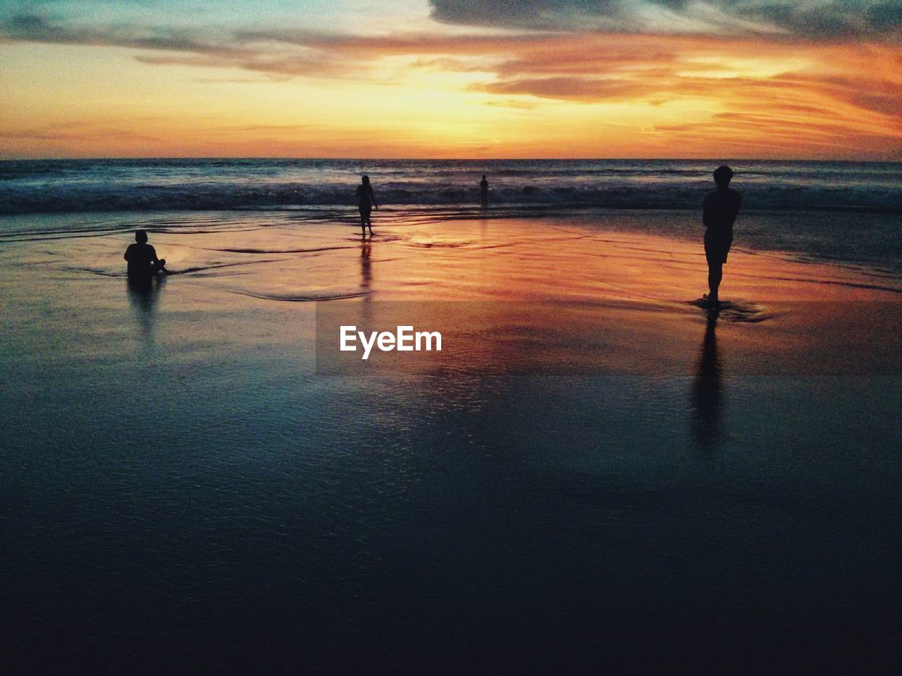 Silhouette of people on beach at sunset