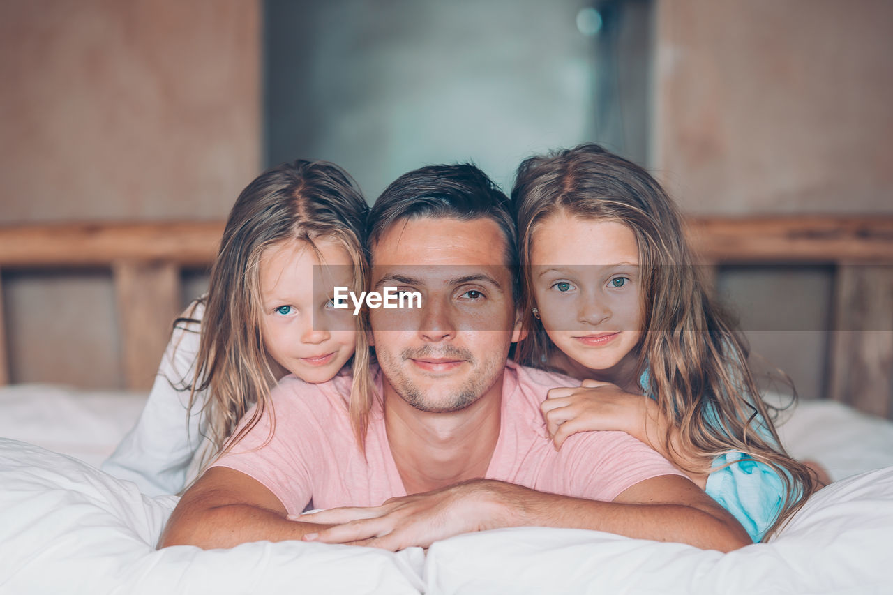 Portrait of father with daughters on bed