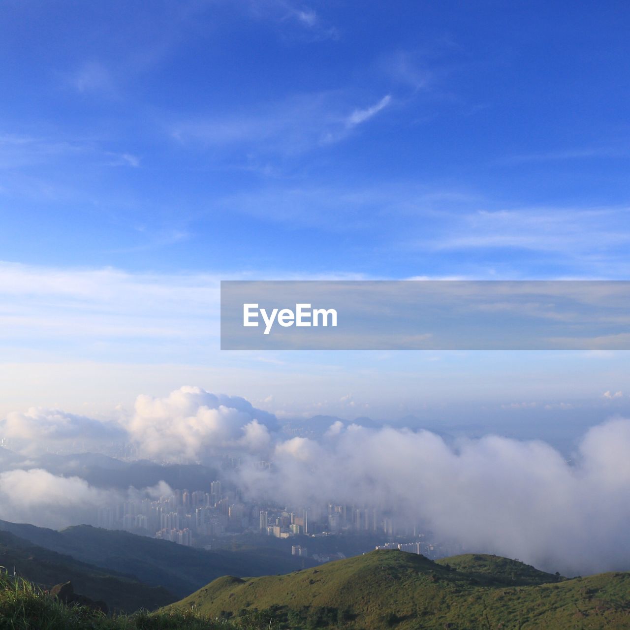 High angle view of cityscape covered with clouds against blue sky