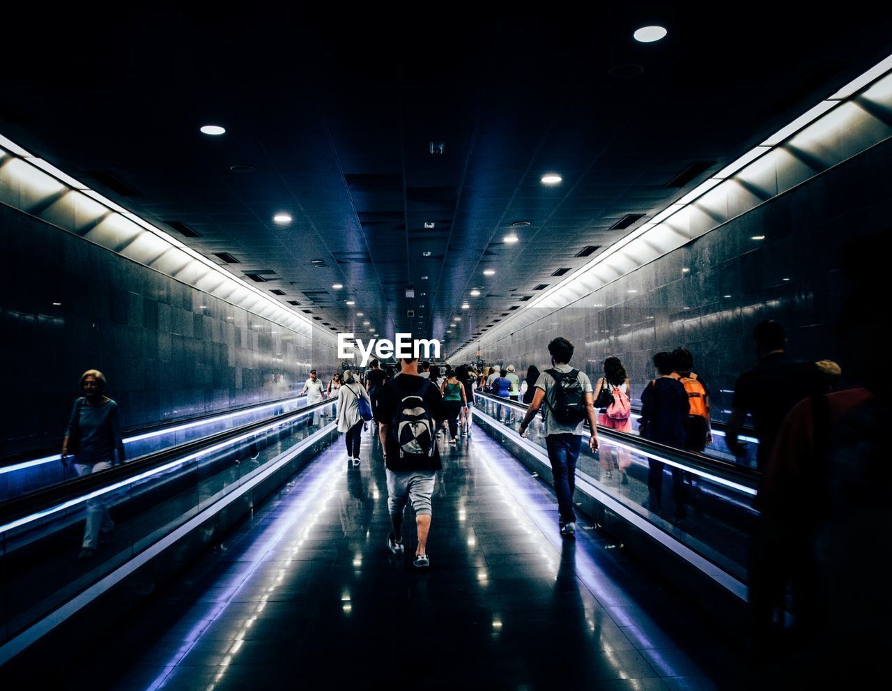People walking at illuminated underground walkway