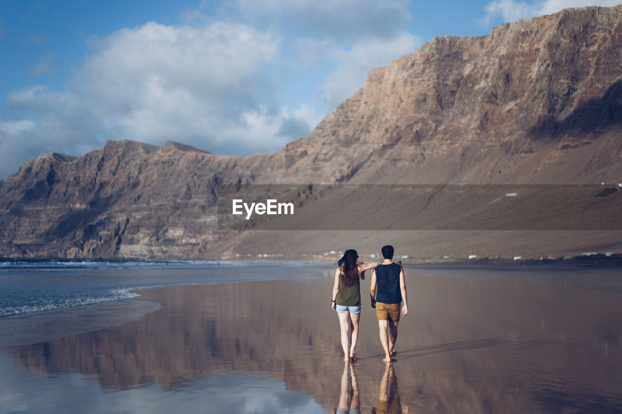 Rear view of a couple with mountain against sky