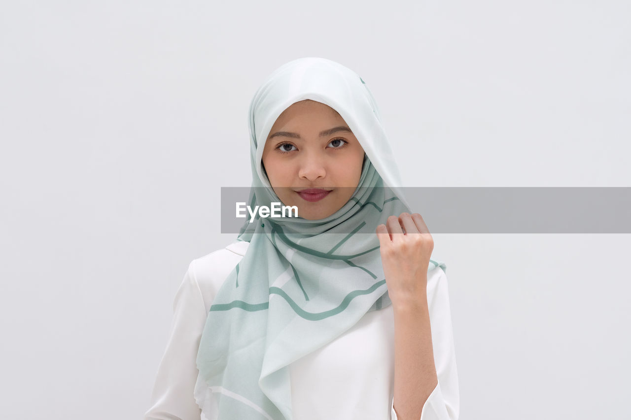 Portrait of smiling girl standing against white background