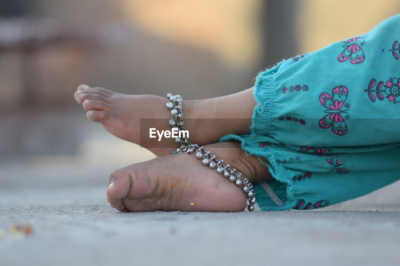 LOW SECTION OF WOMAN WITH HAND ON ROCK