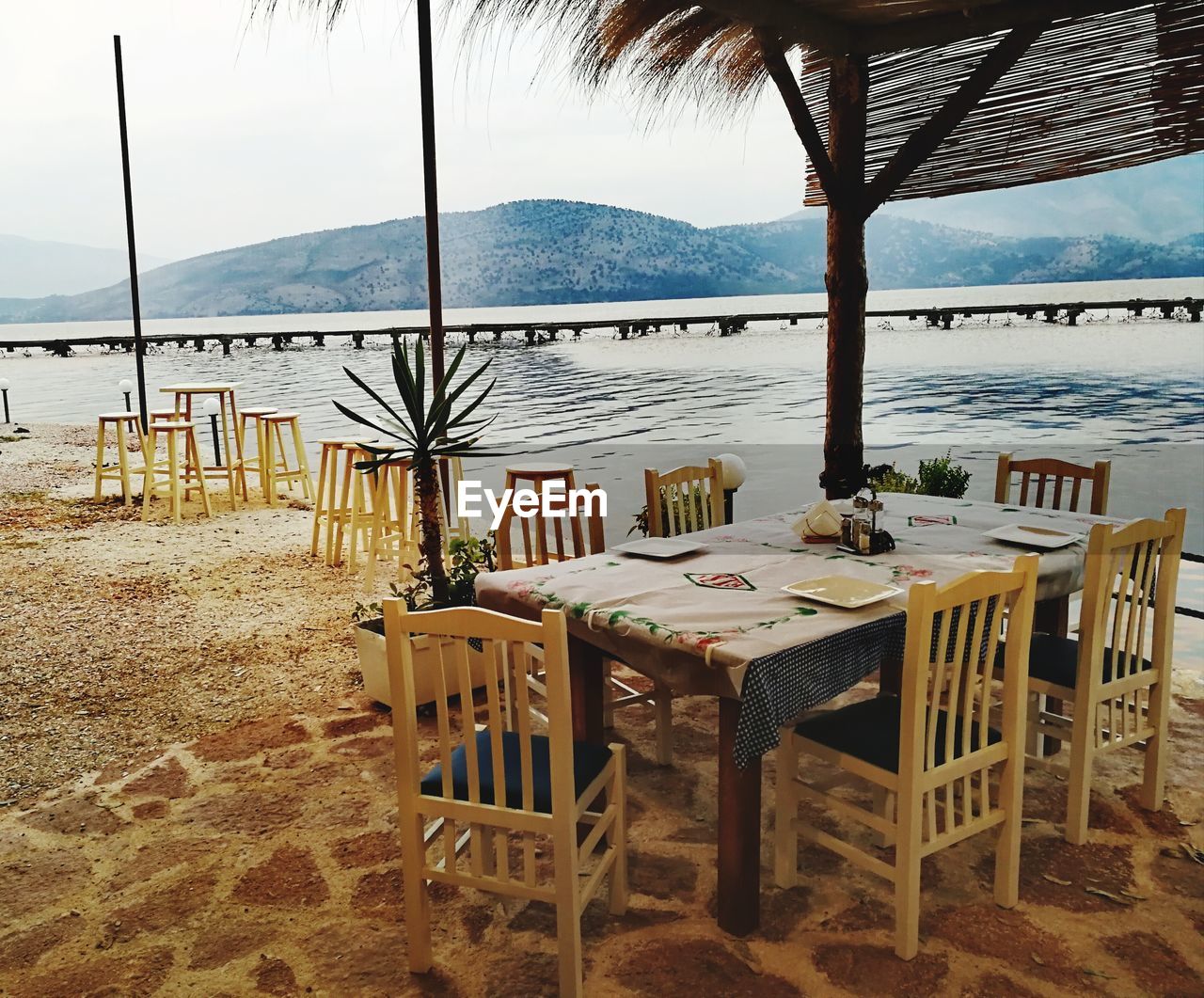 CHAIRS AND TABLE BY SEA AGAINST SKY