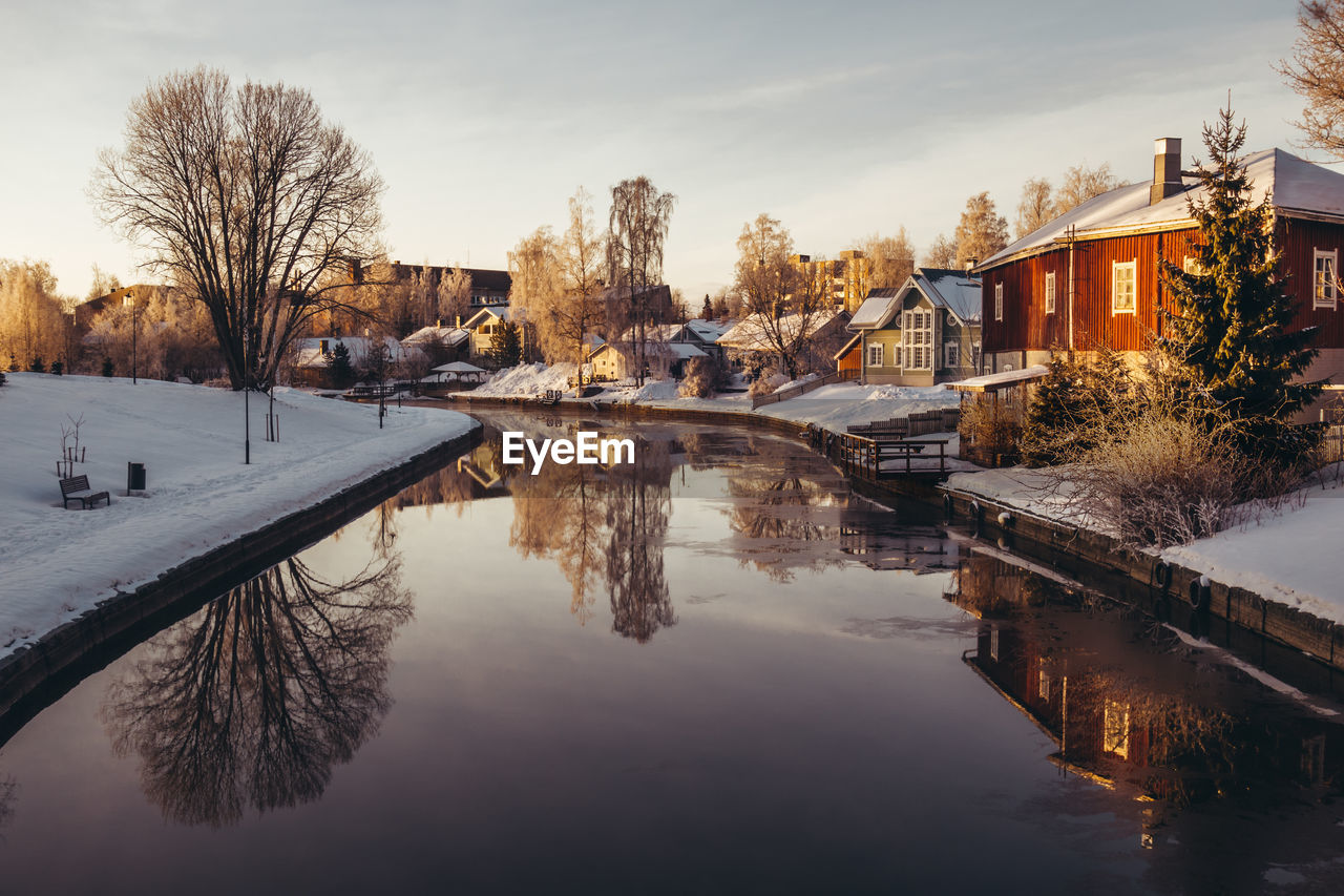 Scenic view of buildings by canal against sky during winter