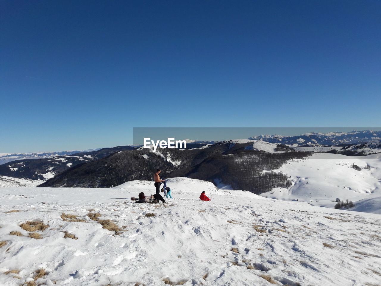 People on snowcapped mountain against clear sky