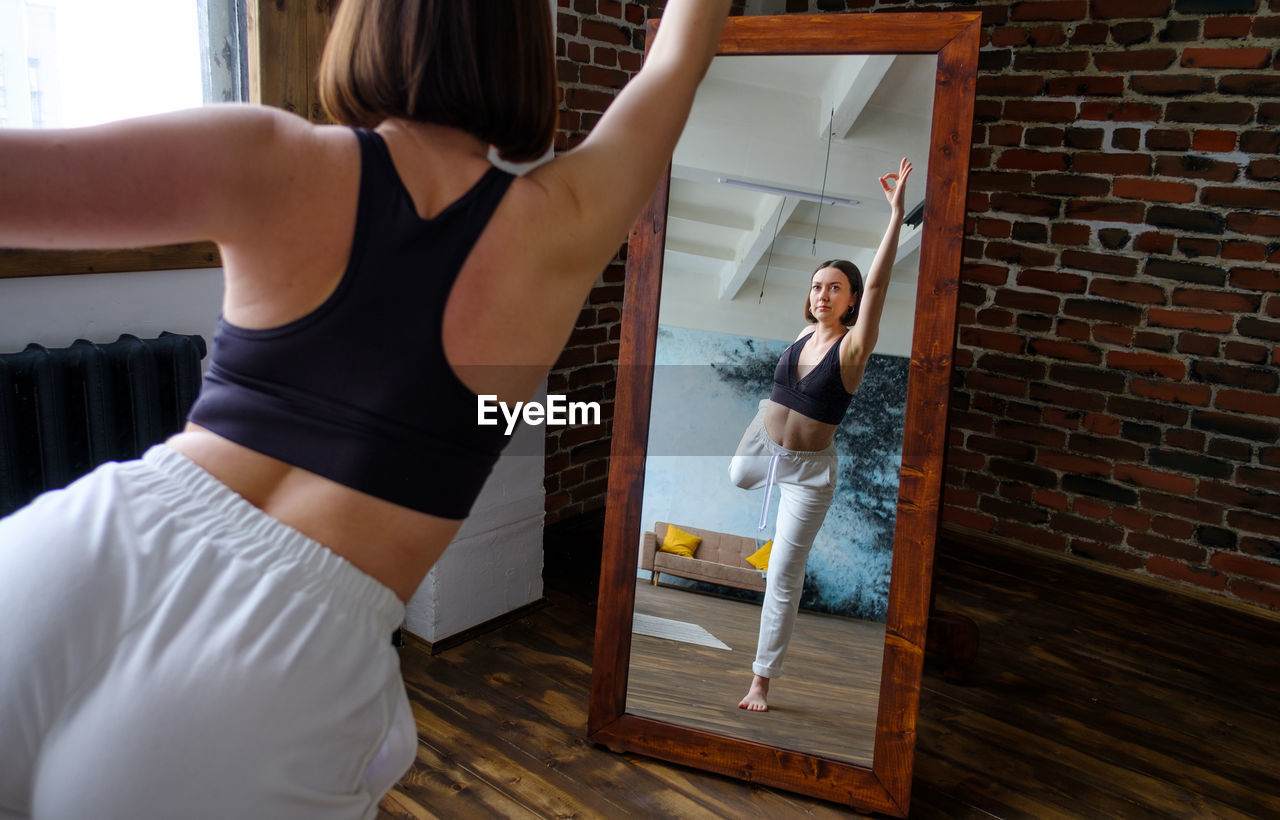 YOUNG WOMAN STANDING ON FLOOR AT HOME