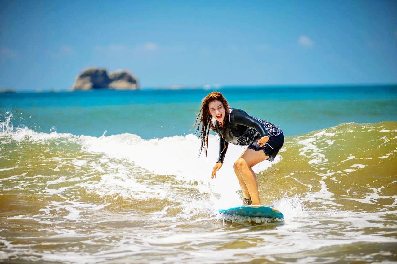 Full length of woman surfing on wave at sea